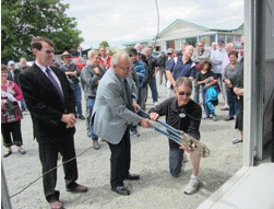 Menz Shed Steering Committee project manager Terry Cummock helps Mayor Sowman snip the wire at the opening ceremony.